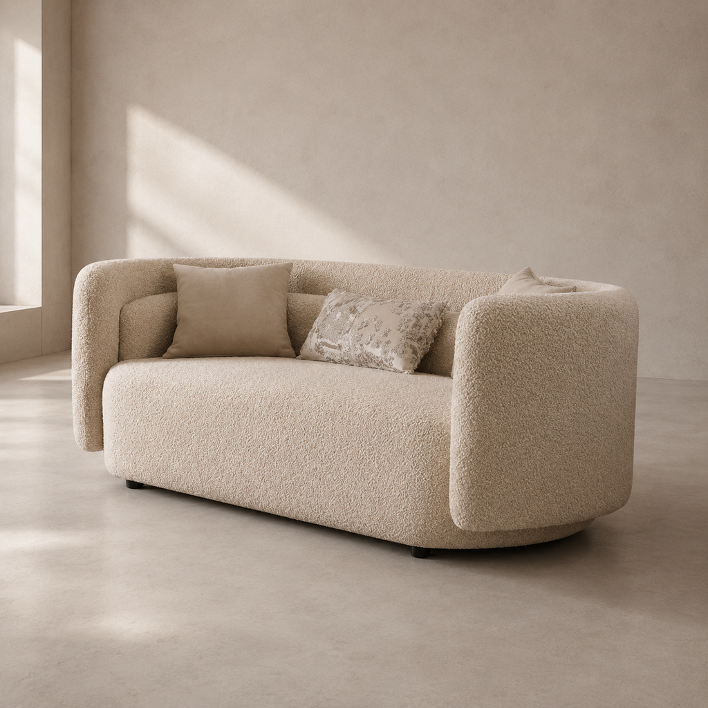 A modern curved loveseat sofa upholstered in textured boucle fabric, shown in a minimalist room with warm sunlight and shadow on a neutral beige wall and floor.