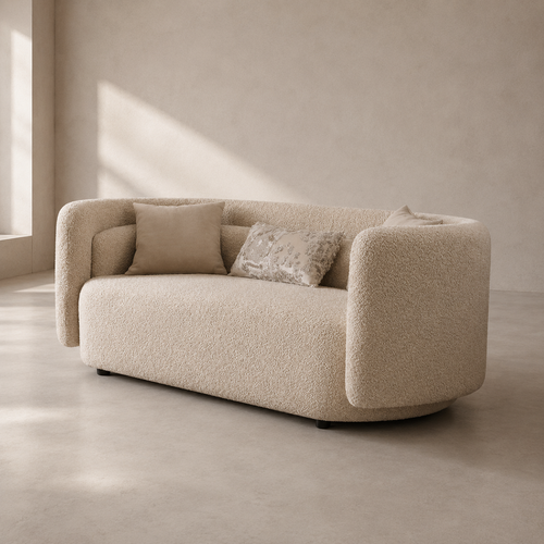 A modern curved loveseat sofa upholstered in textured boucle fabric, shown in a minimalist room with warm sunlight and shadow on a neutral beige wall and floor.