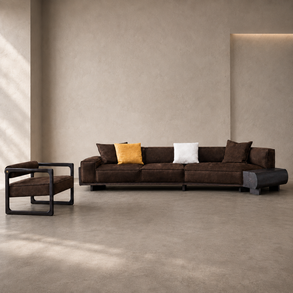 A modern dark brown fabric sofa with black metal frame legs, styled with a mustard yellow pillow and a white throw pillow, set in a minimalist beige room alongside a matching armchair.