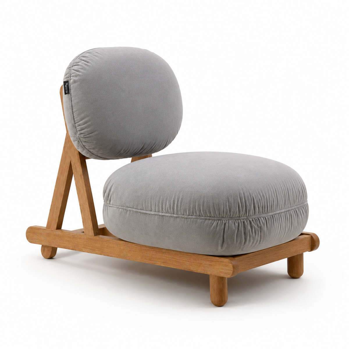 A modern low-profile lounge chair featuring thick, round gray cushions on a light natural wood frame, photographed against a seamless white background.